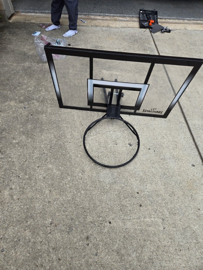 A partially assembled portable basketball hoop by Mount & Fix DFW